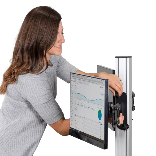 Woman adjusting dual monitor mount on electric standing desk with graph on screen