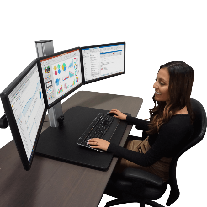 Woman working at a high-rise electric standing desk with triple monitors in an office setting