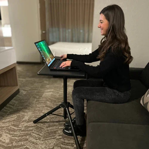 Woman using laptop on high-rise mobile tripod standing desk in modern office