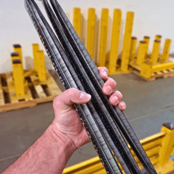 A hand holding several Victor ProSpan magnetic measuring tools in a warehouse setting.
