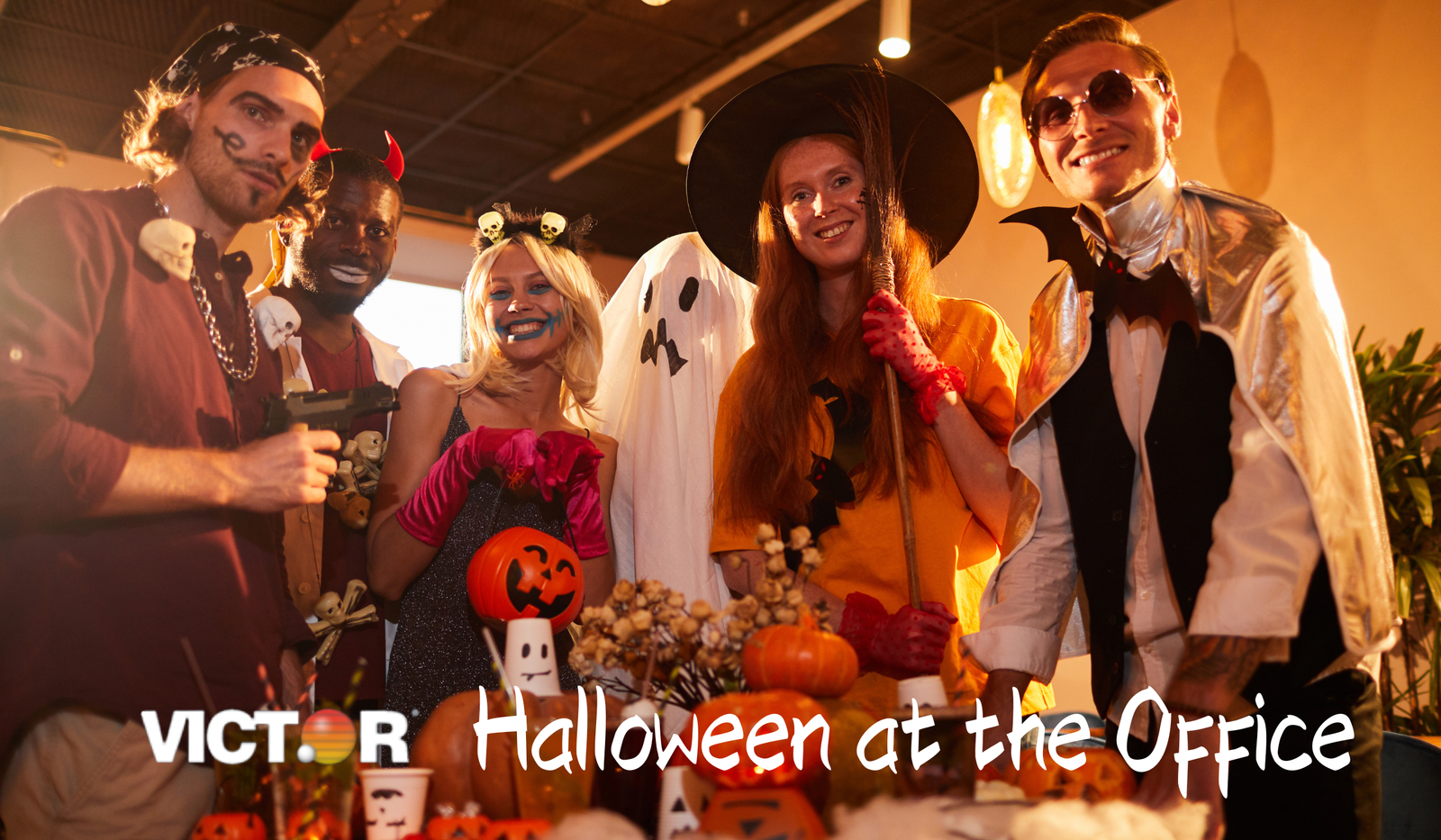 Group of coworkers in Halloween costumes at decorated office with pumpkins and festive props