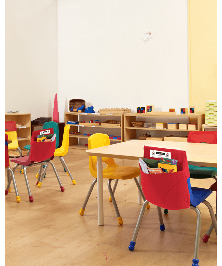 Colorful classroom chairs with red seat sacks around a wooden table