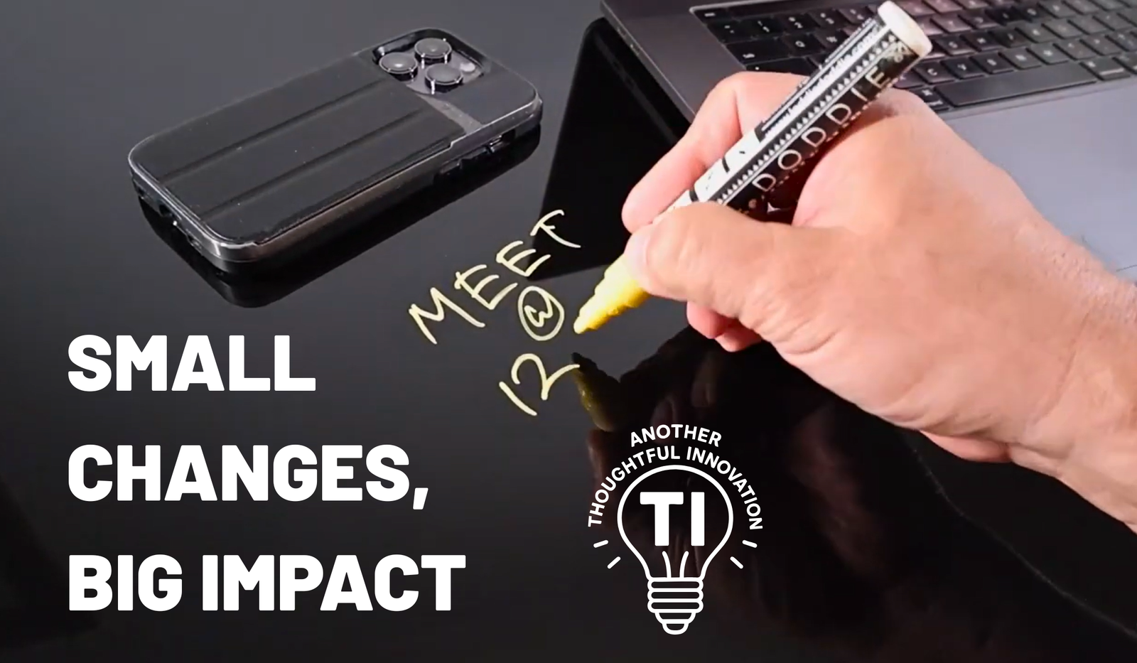 Hand writing meeting note on black glass desk with phone and laptop nearby, workspace innovation