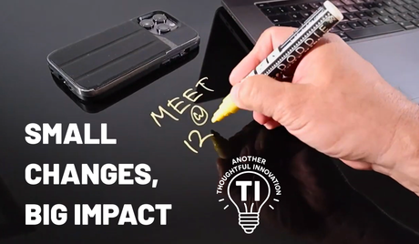 Hand writing meeting note on black glass desk with phone and laptop, promoting workspace innovation