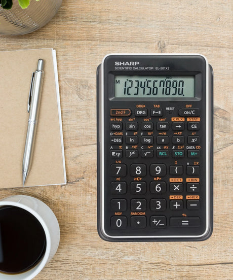 Scientific calculator on wooden desk with notebook, pen and coffee cup