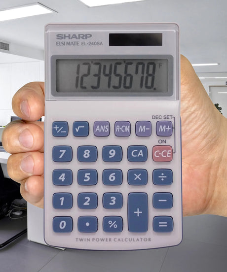 Hand holding Sharp calculator in modern office, calculator display showing numbers