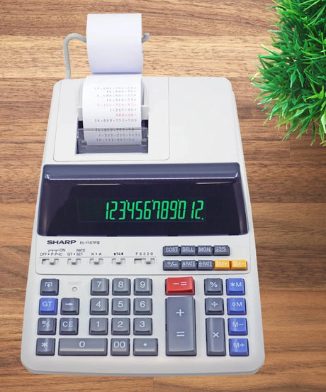 Desktop printing calculator with paper roll on wood desk, green plant nearby, office setting