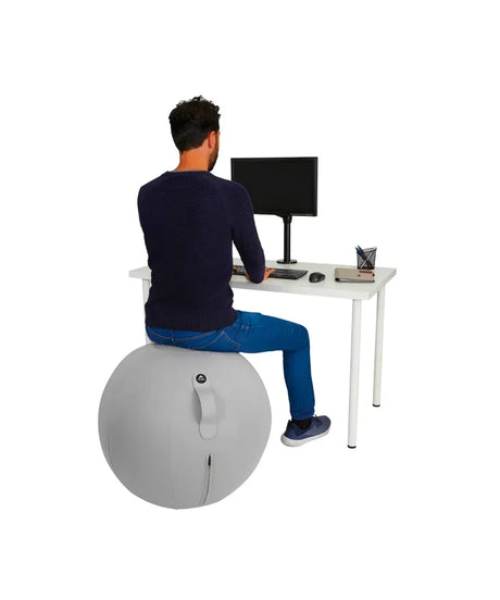Man sitting on a grey MoveHop ergonomic balance ball chair at a white office desk.