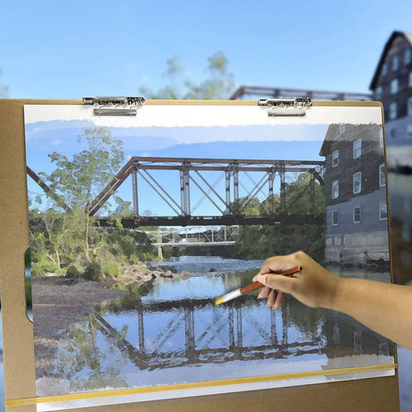 Artist sketch board with hand painting a landscape of a bridge over a river