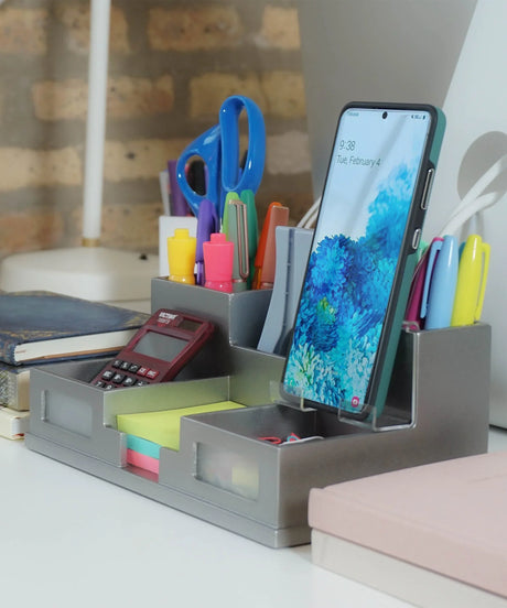 Desk organizer with pens, scissors, calculator, sticky notes, and smartphone on office workspace