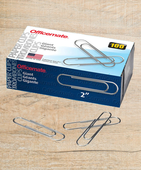 Box of 2-inch giant silver paper clips with loose clips on a wooden surface, 100 count