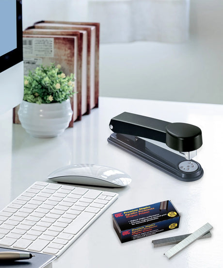 Black desktop stapler and premium staples on modern office desk with keyboard and mouse