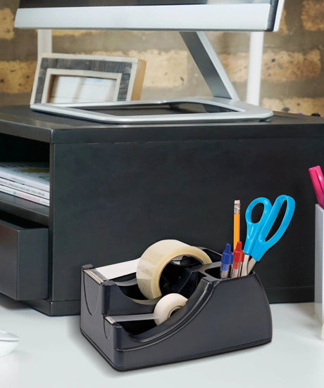 Black tape dispenser organizer with pens, scissors, and tape rolls on an office desk