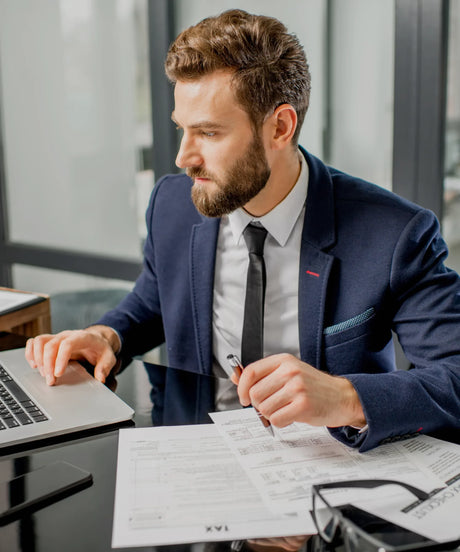 Professional accountant reviewing tax forms at a desk with laptop and paperwork