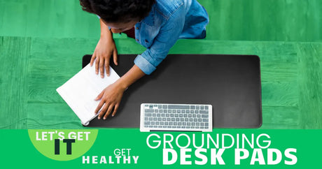Person working at desk with large black grounding desk pad, keyboard, and notebook, top view