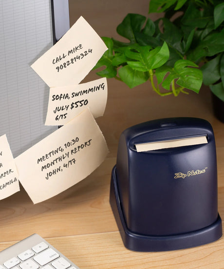 Desk scene with Zip Notes dispenser, handwritten reminder notes, keyboard, and green plant.
