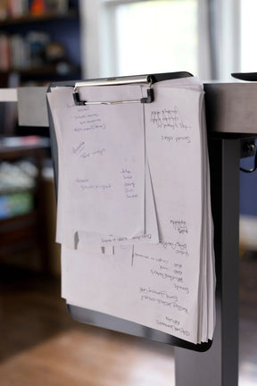 Handwritten notes on a clipboard attached to a Victor® Technology standing desk.