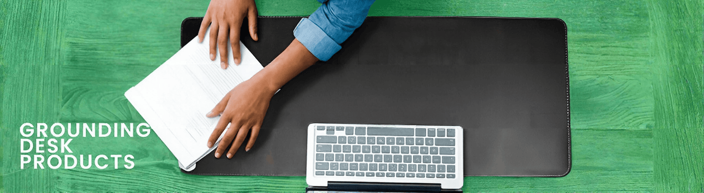 Person using a grounding desk mat with a keyboard and laptop on a green surface