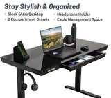 Black glass desk with laptop, phone, and other items on a white background