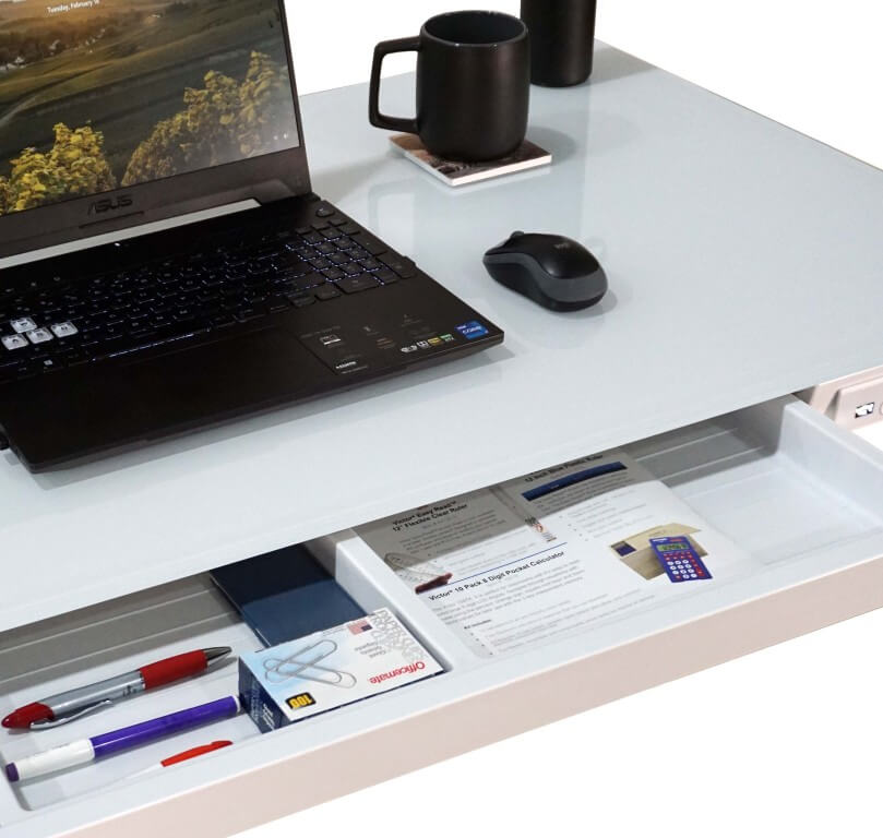 Laptop on a desk with a drawer open, showing office supplies.