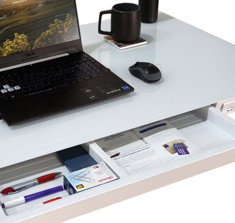 Laptop on a desk with a drawer open, showing office supplies.
