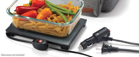 Glass container with food on a portable hot plate with power cord, on a white background.