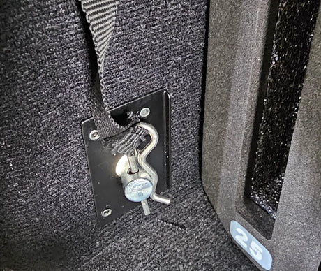 Close-up of a cotter key securing a black strap to a metal anchor plate inside of the Vaultz cell phone locker
