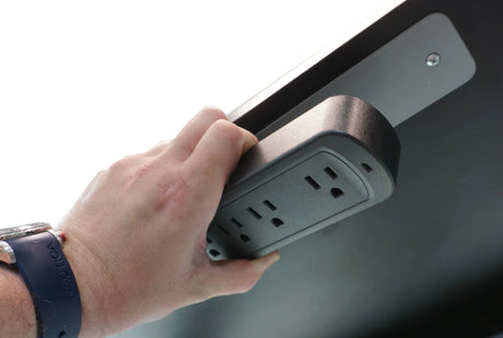 A hand holding a Victor MagnetPlus Magnetic Power Strip attached to a metal surface.