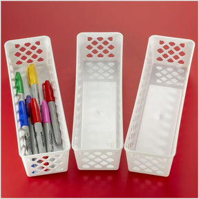 Three long white Officemate® Achieva supply baskets, one containing colorful markers.