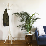 White wood coat stand with jacket beside plant, marble side table, and blue sofa in modern room