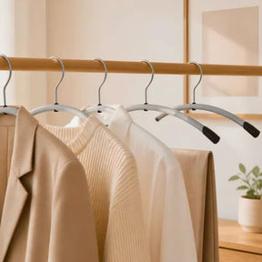 Set of Alba heavy-duty metal clothes hangers with ABS shoulder tips holding neutral-toned apparel.