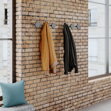 Modern wall coat rack with round pegs and umbrella hook mounted on brick wall in office space.
