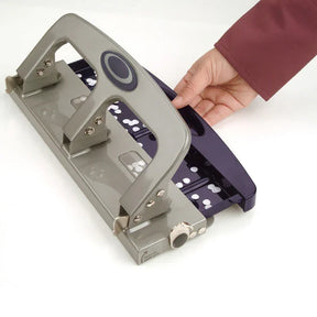 Hand operating an Officemate Deluxe 3-Hole Punch on a white surface
