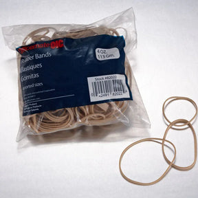 A clear plastic bag of Officemate assorted sizes rubber bands with a few loose bands beside it.