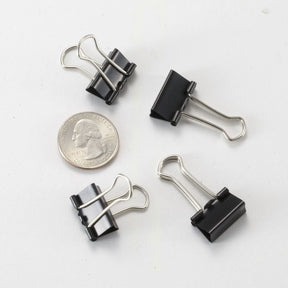 Four Officemate Small Black Binder Clips surrounding a US quarter for scale.