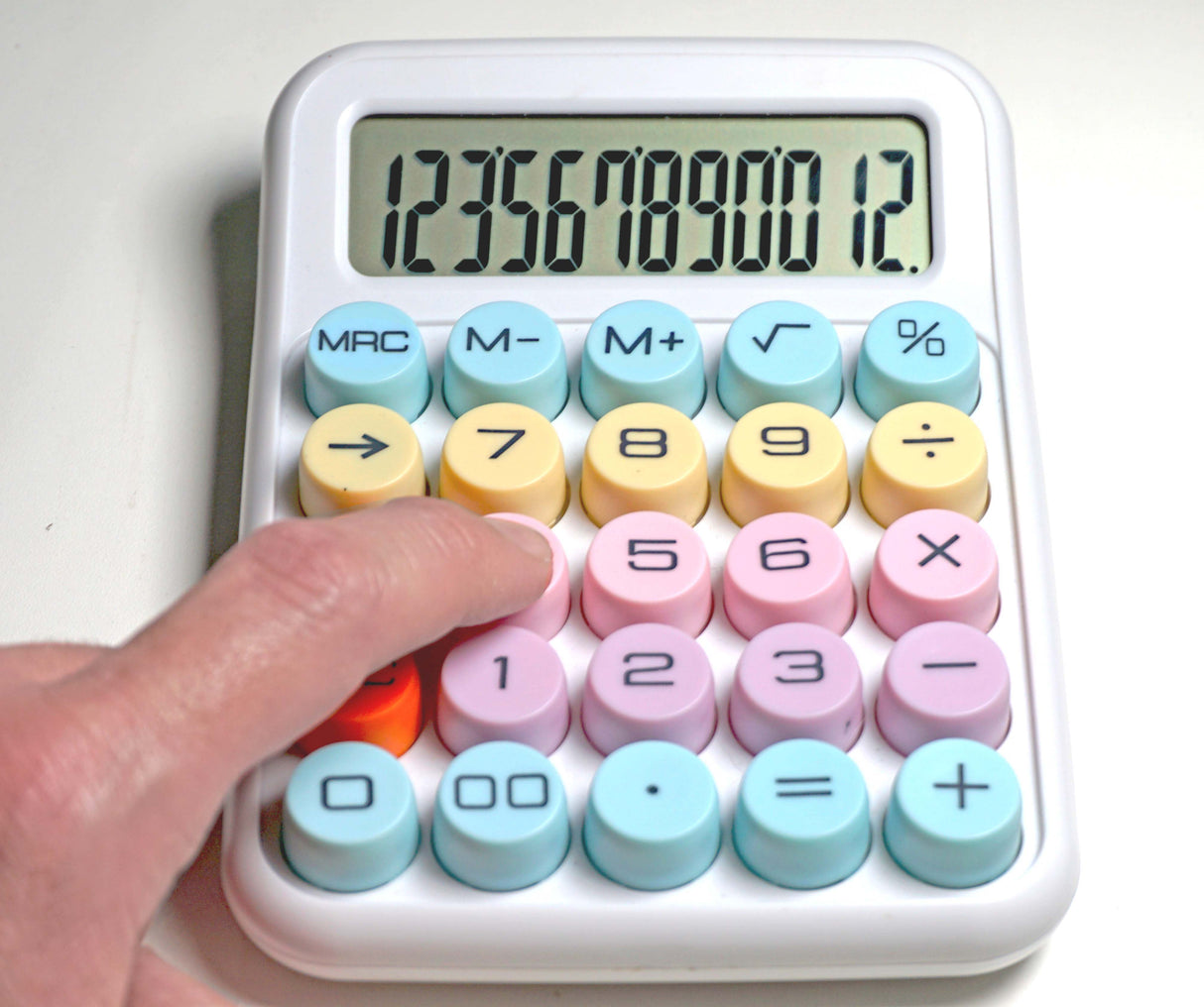 Hand pressing button on pastel desktop calculator with large display and round keys