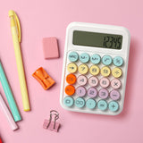 Colorful desktop calculator with pastel buttons and stationery on a pink background