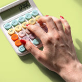 Hand pressing pastel button desktop calculator on light green workspace