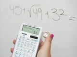 Person using a white scientific calculator to solve a math equation on a whiteboard.